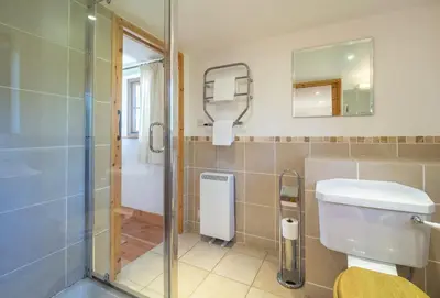 a bathroom with a toilet and a glass shower at Church Close Cottage in Gwennap