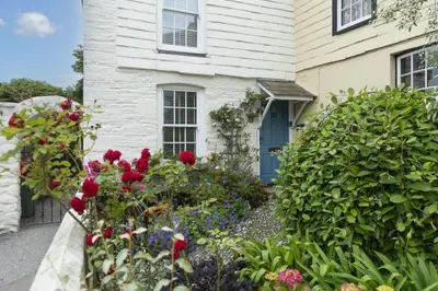 a house with a garden of flowers in front of it at Cob Cottage in St. Agnes