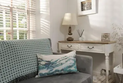 a living room with a chair with a pillow on it at Cob Cottage in St. Agnes