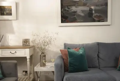 a living room with a couch and a table with wine glasses at Cob Cottage in St. Agnes