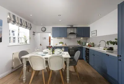 a kitchen with blue cabinets and a table and chairs at Cob Cottage in St. Agnes