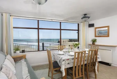 a dining room with a table and a view of the ocean at Cliff Cottage in Gorran Haven