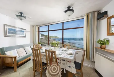 a dining room with a table and a view of the ocean at Cliff Cottage in Gorran Haven