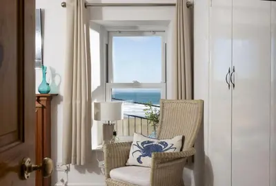 a chair with a pillow in a room with a window at Cliff Cottage in Gorran Haven