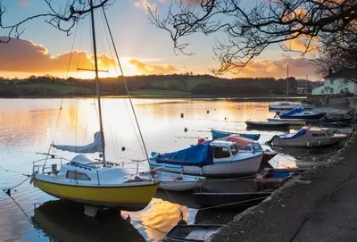 a group of boats docked in the water at sunset at Cliff Cottage in Gorran Haven