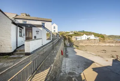 a view of a beach with a house and a fence at Cliff Cottage in Gorran Haven