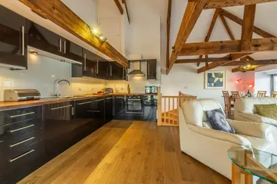 a kitchen and living room with a couch and a table at Copperhouse View in Hayle