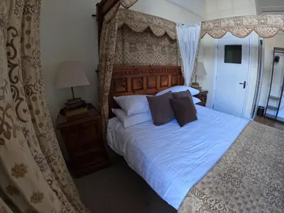 a bedroom with a canopy bed with white sheets and pillows at The Grove Falmouth in Falmouth