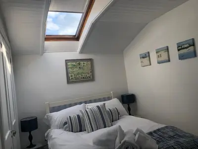 a bedroom with a bed and a skylight at Bay House Lundy Port Isaac Apartment with Sea Views & Parking in Port Isaac