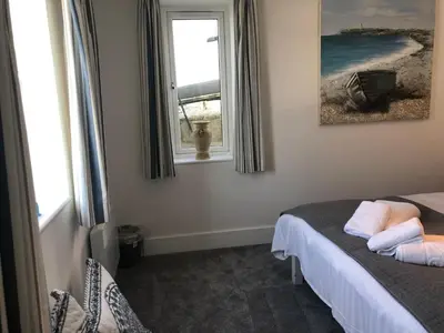 a bedroom with a dog looking out a window at Bay House Lobber Port Isaac Apartment with Sea Views & Parking in Port Isaac