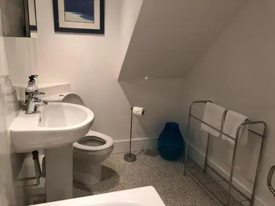 a white bathroom with a sink and a toilet at Bay House Lobber Port Isaac Apartment with Sea Views & Parking in Port Isaac