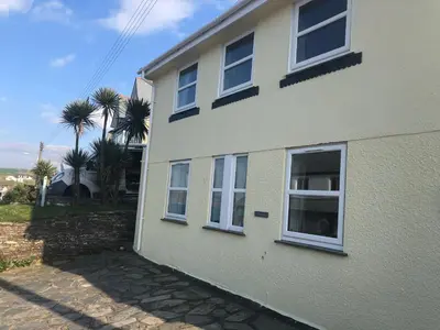 a white house with white windows and palm trees at Bay House Lobber Port Isaac Apartment with Sea Views & Parking in Port Isaac