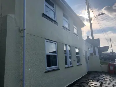 a white building with windows on the side of it at Bay House Lobber Port Isaac Apartment with Sea Views & Parking in Port Isaac
