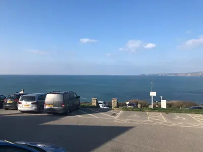 a parking lot with cars parked next to the ocean at Bay House Lobber Port Isaac Apartment with Sea Views & Parking in Port Isaac