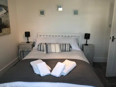 a bedroom with a bed with two towels on it at Bay House Lobber Port Isaac Apartment with Sea Views & Parking in Port Isaac