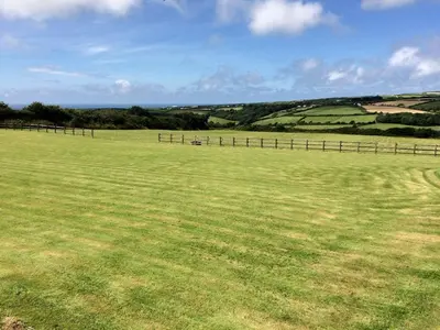 a large grass field with a fence in the distance at Courtyard Farm Cottages in Boscastle