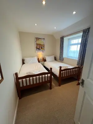 two twin beds in a room with a window at Courtyard Farm Cottages in Boscastle