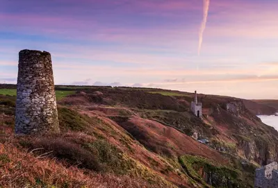 a stone tower on a hill with a castle at Dolphins in Coverack