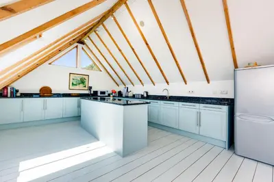 a kitchen with white cabinets and a roof at Dolphins in Coverack
