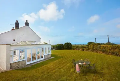 a house with a table on a grass field at Balwest Cottage in Helston
