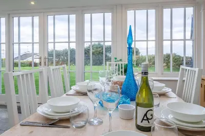 a dining room table with a bottle of wine and glasses at Balwest Cottage in Helston