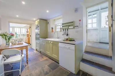 a kitchen with green cabinets and a table and a sink at Balwest Cottage in Helston