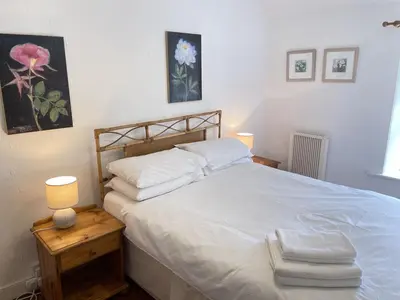 a bedroom with a large white bed with two lamps at Porthia Cottage in St Ives