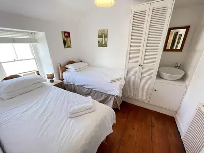 a bedroom with two beds and a sink in it at Porthia Cottage in St Ives