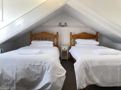 two beds in a attic room with white sheets at Porthia Cottage in St Ives