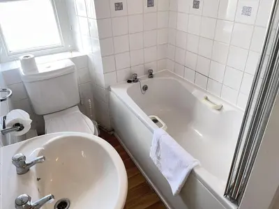 a bathroom with a white tub and a sink and a toilet at Porthia Cottage in St Ives