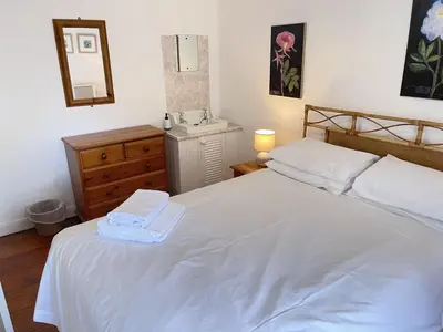 a bedroom with a white bed and a sink at Porthia Cottage in St Ives