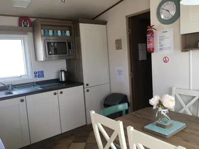 a kitchen with a table with a vase of flowers on it at BRANWOOD Luxury Caravan Holidays Newquay in Newquay