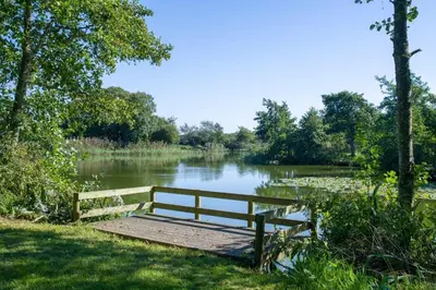 a wooden bench sitting on a dock next to a lake at BRANWOOD Luxury Caravan Holidays Newquay in Newquay