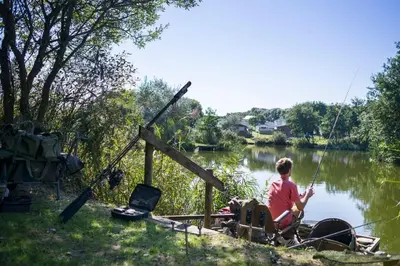 a person sitting on a boat fishing on a river at BRANWOOD Luxury Caravan Holidays Newquay in Newquay