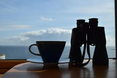 a coffee cup on a table with a view of the ocean at Skysail - Exceptional Sea Views in Mevagissey