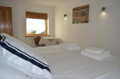 a bedroom with a white bed with towels on it at Skysail - Exceptional Sea Views in Mevagissey