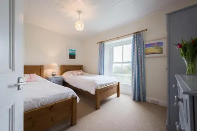 two beds in a room with a window at Popham Cottage in Cornwall in Newquay