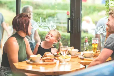 a group of people sitting at a table with food at Popham Cottage in Cornwall in Newquay