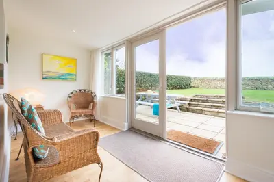 a living room with a door leading to a patio at Popham Cottage in Cornwall in Newquay