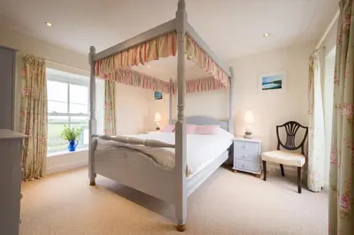 a bedroom with a canopy bed and a window at Popham Cottage in Cornwall in Newquay