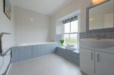 a white bathroom with a sink and a window at Popham Cottage in Cornwall in Newquay