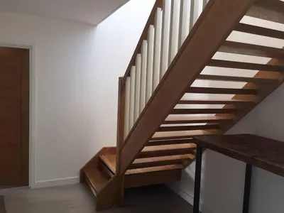 a wooden staircase in a room with a wooden table at Relax in style at my stunning Holywell Beach home in Holywell Bay