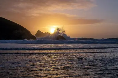 a sunset on the beach with the waves at Harbour Lights in Newquay