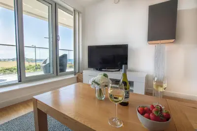 a living room with a table with two glasses of wine at Harbour Lights in Newquay