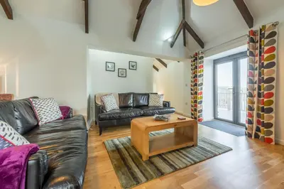 a living room with a leather couch and a coffee table at Hunter's Barn in St. Agnes