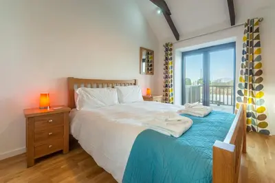 a bedroom with a bed with a blue blanket and a window at Hunter's Barn in St. Agnes