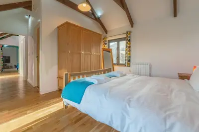 a bedroom with a large bed and a wooden cabinet at Hunter's Barn in St. Agnes