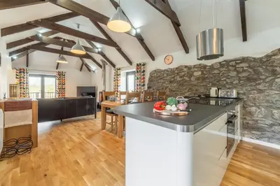 a kitchen and living room with a stone wall at Hunter's Barn in St. Agnes
