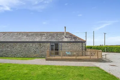 a stone building with a porch and a deck at Hunter's Barn in St. Agnes