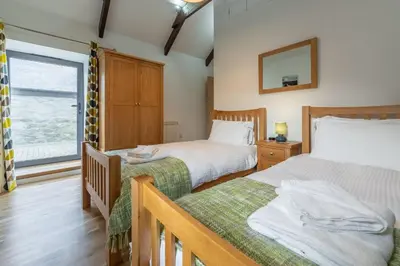 a bedroom with two beds and a window at Hunter's Barn in St. Agnes